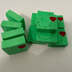 four green boxes with red hearts on them and one has a frog face painted on it