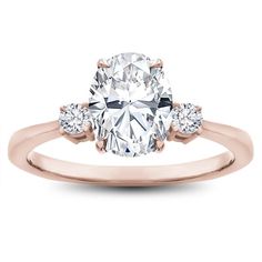 a rose gold engagement ring with an oval cut diamond and three stones on the side