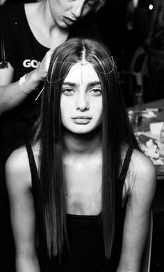 a woman is getting her hair cut by another woman in the background at a salon