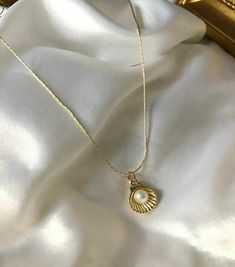 Embrace the elegance of the ocean with this Gold-Plated Pearl Shell Necklace. This elegant piece features a beautifully crafted shell necklace that houses a lustrous pearl. Perfect for beach lovers and those who appreciate the subtle beauty of the sea, this necklace is perfect for both everyday and special occasion wear. The gold-plated chain adds a touch of elegance, making it a timeless addition to your jewelry collection or a thoughtful gift for someone special. Details: * Color: Gold * Material: Gold-plated alloy, imitation pearl * Pendant Size: Approx. 1 cm x 1 cm (shell and pearl) * Chain Length: 45 cm (18 inches) with adjustable extension * Closure: Parrot clasp * Care Instructions: Avoid contact with water, perfume and other chemicals. Store in a dry place when necklace is not in u Elegant Cheap Shell Necklaces, Shell Gold Necklace, Elegant Shell-shaped Pearl Drop Necklace, Pearl Pendant Shell As Gift, Pearl Pendant Shell Gift, Pearl White Shell With Pearl Charm, Pearl Shell With Pearl Charm, Elegant Pearl White Jewelry For Beach, Elegant Mother Of Pearl Shell With Pearl Pendant