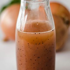 a glass jar filled with liquid sitting on top of a white table next to oranges