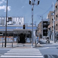 a person riding a bike down the street in front of a lawe store on a sunny day