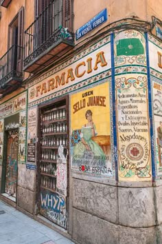 an old building with posters on the front and side windows that read, farmacia