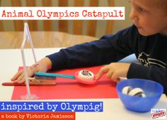 a young boy sitting at a table with an object in front of him that says, animal olympics catapult inspired by olympic