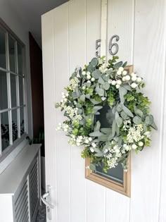 a wreath hanging on the side of a building with numbers and flowers around it,