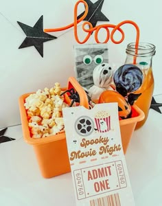 an orange box filled with popcorn and movie tickets next to a sign that says booo