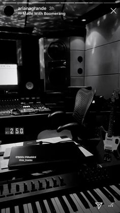 a black and white photo of a music studio with keyboard, monitor, guitar, sound board and other musical equipment