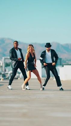 three people are dancing on the roof of a building