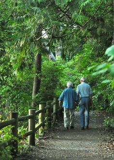 two people walking down a path in the woods