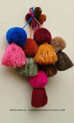 multicolored pom - poms hanging from the side of a white wall