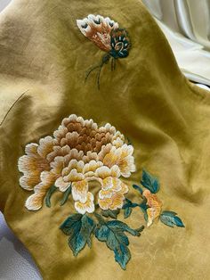 an embroidered piece of cloth with flowers and butterflies on it, sitting on a bed