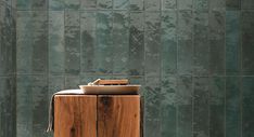 a wooden cabinet sitting in front of a green wall with a bowl on top of it