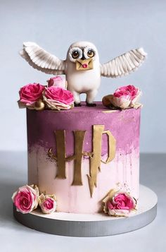 a cake decorated with pink roses and an owl on top is shown in front of a gray background