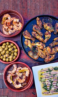 various dishes of food on a table with olives, shrimp and other foods in bowls