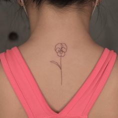 a woman's back neck with a small flower tattoo on her left side ribcage