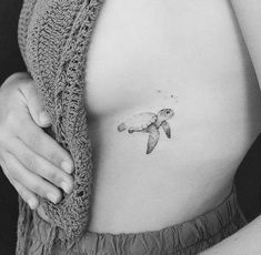 a black and white photo of a woman's stomach with a turtle tattoo on it