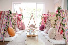 a room filled with lots of pillows and blankets on top of a rug next to a window