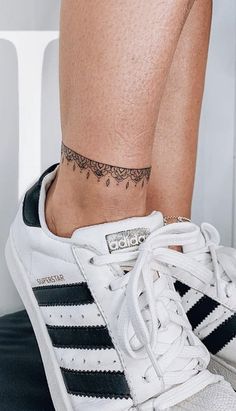 a woman's foot with a small tattoo on her left ankle and black and white striped sneakers