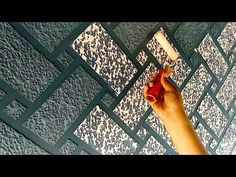 a hand holding a paint roller in front of a tiled wall