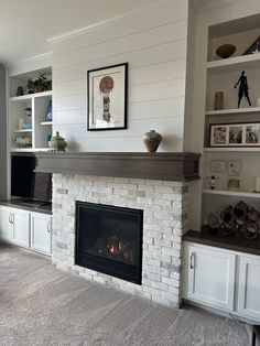 a living room with a fire place and shelves on either side of the fireplace that is built into the wall