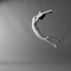 a person jumping in the air while wearing a leotard and holding onto an umbrella