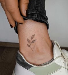 a woman's foot with a small flower tattoo on it