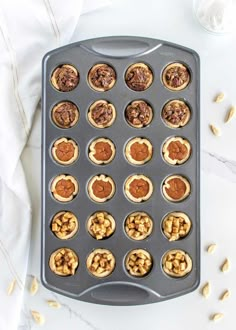 a muffin tin filled with mini cupcakes on top of a white table