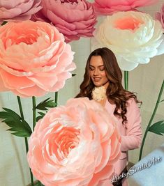 a woman standing in front of large pink and white flowers