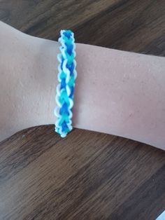 a close up of a person's arm wearing a blue and white beaded bracelet