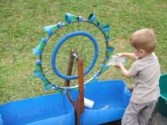 a young boy is playing with a water wheel