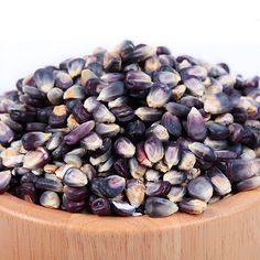 a wooden bowl filled with purple and white corn