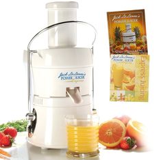 a white juicer sitting on top of a counter next to oranges and strawberries