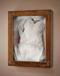 a wedding dress is in a wooden frame