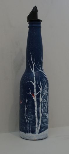 a blue vase with white trees painted on the front and bottom, sitting against a wall