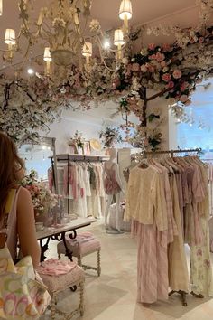 a woman looking at dresses on display in a clothing store with chandeliers hanging from the ceiling