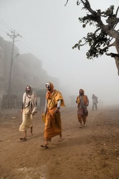 several people walking down a dirt road on a foggy day