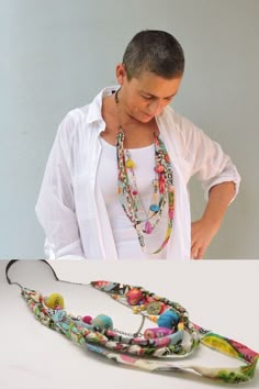 a woman standing next to a white table wearing a multicolored necklace