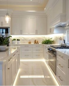 a kitchen with white cabinets and lights on the counter tops, along with an island