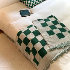 a green and white checkered blanket sitting on top of a bed next to pillows