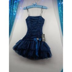 a blue dress hanging up against a wall with lights behind it and a hanger on the wall