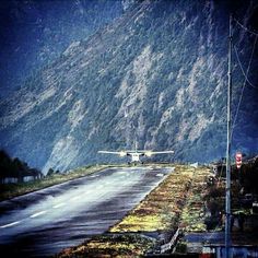 an airplane is taking off from the runway in front of a large mountain side area