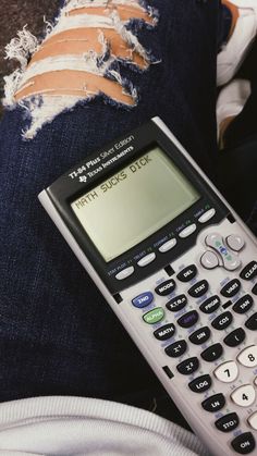 a calculator sitting on someone's leg with ripped jeans