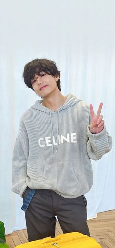 a young man standing in front of a suitcase and making the peace sign with his hand