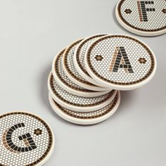 four white and gold coasters with the letter a on them, sitting next to each other