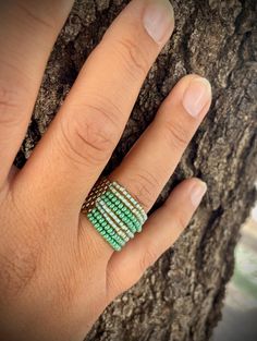 a woman's hand with a ring on it next to a tree