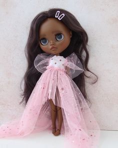 a doll with long hair wearing a pink dress