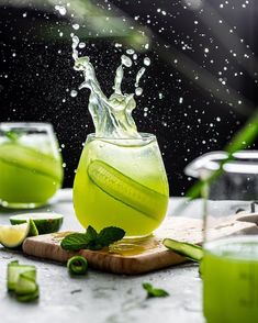 cucumber, mint and lime juice splashing into a glass on a cutting board