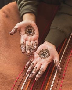 two hands with henna designs on them and one hand holding the other's fingers