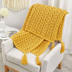 a yellow crocheted blanket sitting on top of a white chair