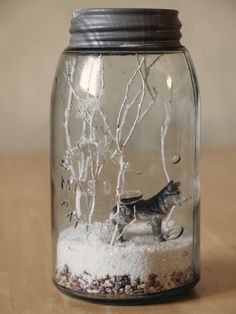 a glass jar filled with snow and a cat figurine